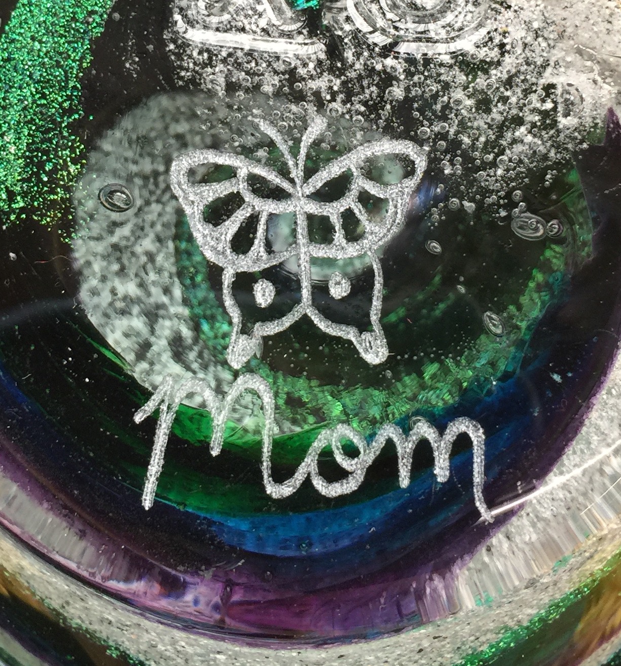 A close up of the word mom written in white on top of a glass.