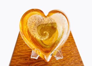 A heart shaped glass dish on top of a wooden table.