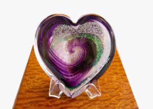 A heart shaped glass dish with purple and green swirls.