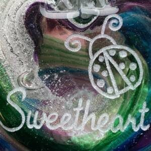 A close up of the word sweetheart on a glass heart