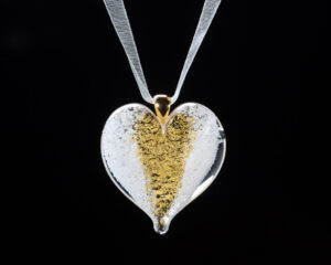 A heart shaped glass pendant with gold leaf.