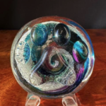 A glass object with swirls and colors on it.