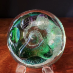 A glass bowl with green and purple swirls.