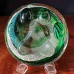 A glass bowl with green and white design on top of a wooden table.