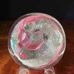 A glass ball with pink and white swirls on it.