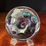 A glass ball with swirls of color on top.