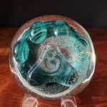 A glass bowl with green leaves on it